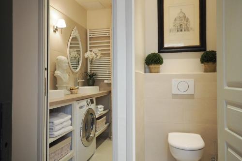 a bathroom with a toilet and a washer and dryer at Saint Germain Elegant ChicSuites in Paris