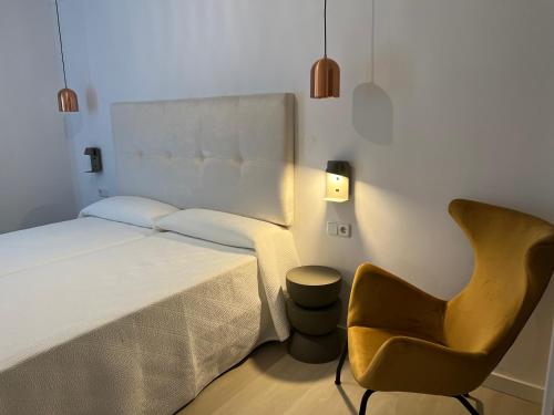 a bedroom with a bed and a chair at Apartamentos Boutique Poniente Playa in San Antonio