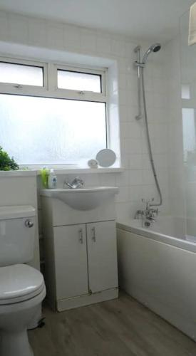 La salle de bains est pourvue de toilettes, d'un lavabo et d'une fenêtre. dans l'établissement Large House - Free Parking - Contractor - Leisure, à Luton