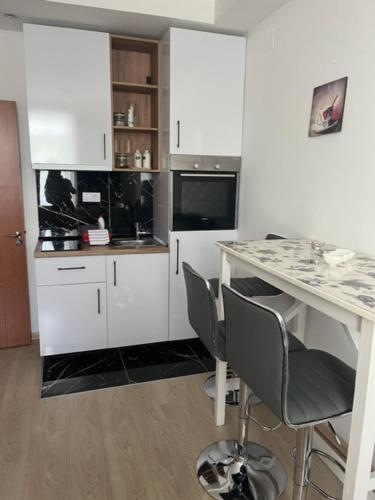 a kitchen with white cabinets and a cat sitting under a desk at Bulevar Star Apartment in Belgrade