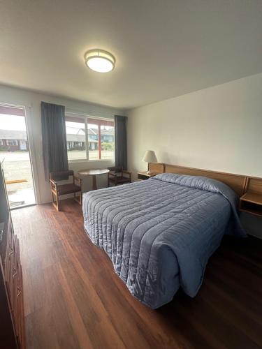 ein Schlafzimmer mit einem großen Bett mit einer blauen Decke in der Unterkunft Captain John's Motel in Charleston