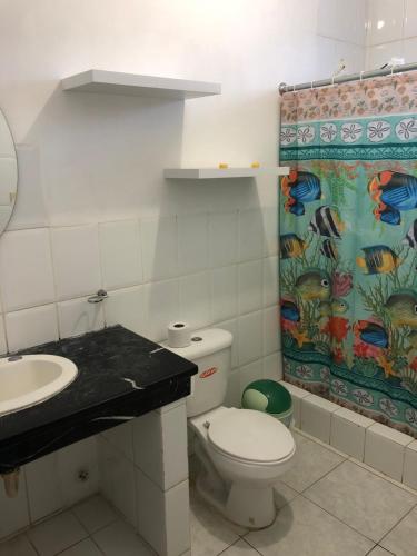 y baño con aseo, lavamanos y cortina de ducha. en Flor de Lis Beach House, villa vacacional, en Playas