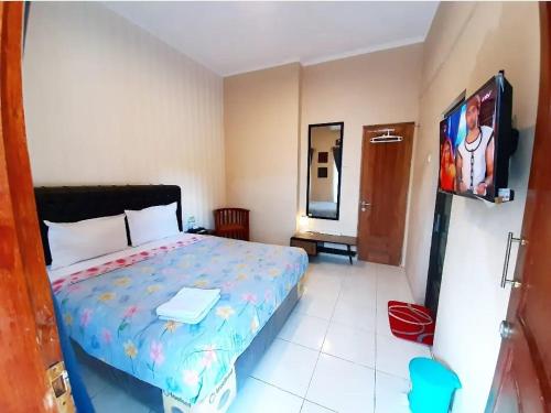 a bedroom with a bed and a flat screen tv at Wijilan60 Syariah in Yogyakarta