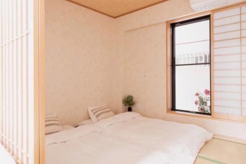 1 dormitorio con cama blanca y ventana en ホテルWakatsuki en Osaka