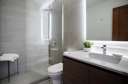 Baño blanco con lavabo y aseo en EL PRAT Luxury Aparment Lima Peru, en Lima
