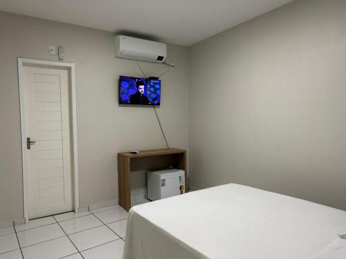 巴雷里尼亞斯的住宿－Pousada Central dos Lençóis，卧室配有一张床,墙上配有电视。