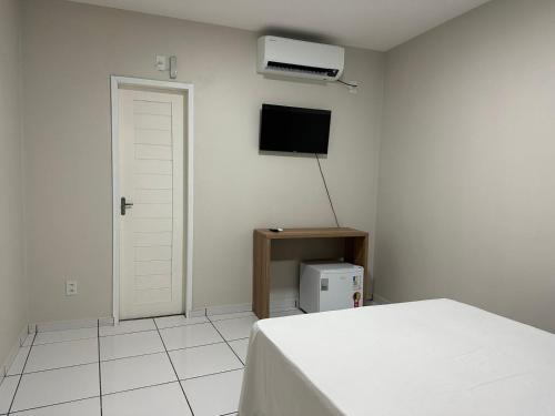 - une chambre blanche avec un lit et une télévision dans l'établissement Pousada Central dos Lençóis, à Barreirinhas