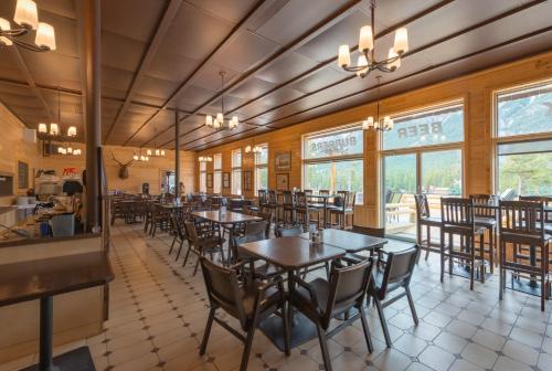 a dining room with tables and chairs and windows at David Thompson Resort in Cline River