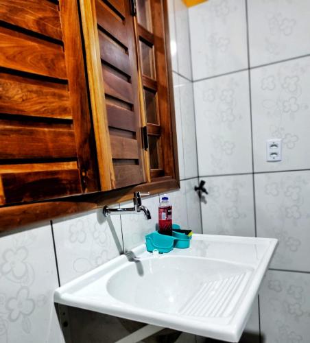 a bathroom with a white sink and a wooden cabinet at Casa temporada Flor de pitanga in Cavalcante