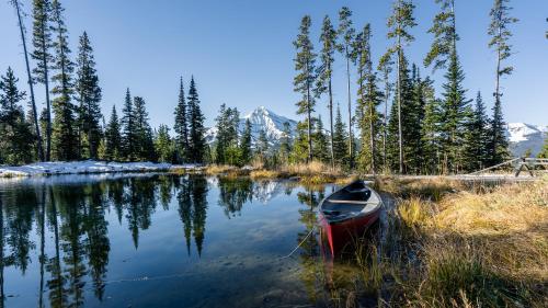 a red canoe sitting on the shore of a lake at Alpine #2 in West Yellowstone