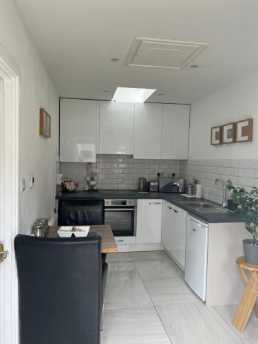 una cocina con armarios blancos y una mesa. en Dannifar Guest House, en Londres