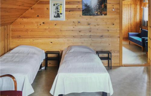 Duas camas num quarto com paredes de madeira em Lovely Apartment In lvdalen With Kitchen em Älvdalen