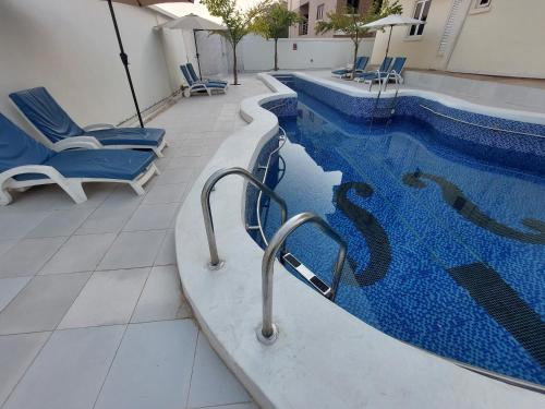 a swimming pool with blue chairs next to a building at Officer Condo Apartments in Yanyan