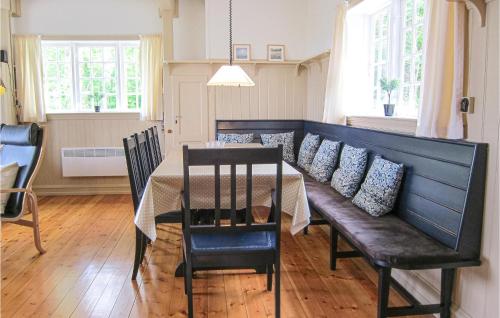 a dining room with a table and a bench and windows at Awesome Home In Gudhjem With Wifi in Gudhjem