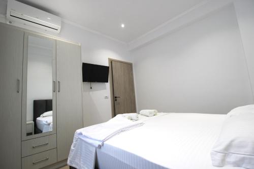 a white bedroom with a bed and a mirror at Garden Vila Ermali in Ksamil