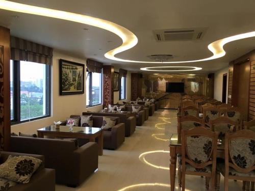 Habitación grande con sofás, mesas y sillas. en Golden Thai binh Hotel, en Thái Bình