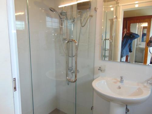 La salle de bains est pourvue d'une douche et d'un lavabo. dans l'établissement KOON COTTAGE, à Kandy