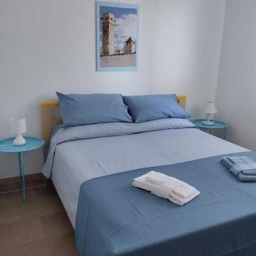 馬蒂納塔的住宿－Diomede Holiday Home，一间卧室配有一张带蓝色床单的床和两张桌子