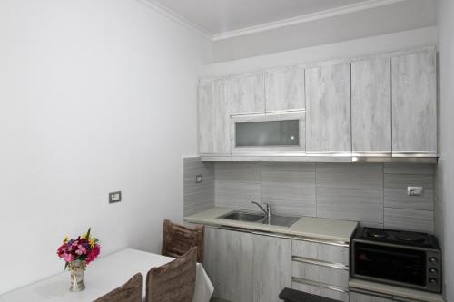 a kitchen with wooden cabinets and a table with flowers on it at Garden Vila Ermali in Ksamil