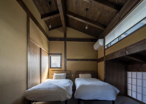 Duas camas num pequeno quarto com uma janela em casa網野 em Kyotango