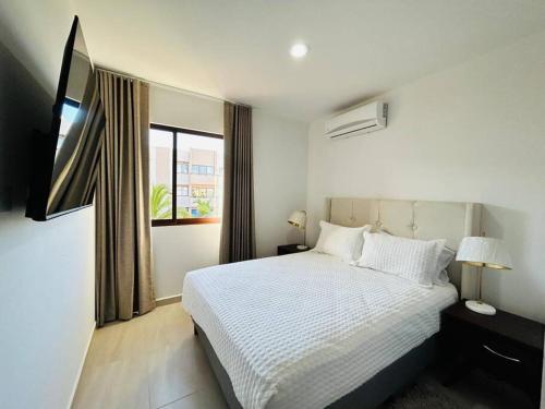 ein Schlafzimmer mit einem weißen Bett und einem Fenster in der Unterkunft 2 min caminando de la playa/pool in Mazatlán