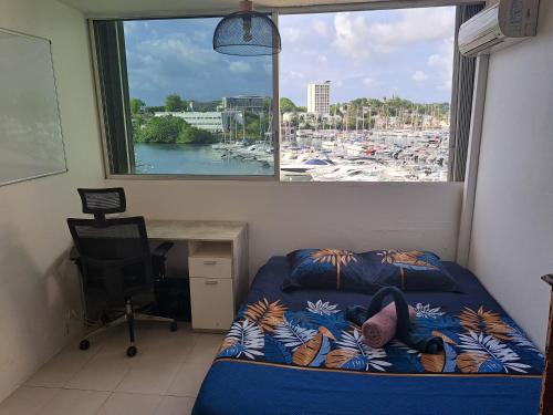 una camera da letto con finestra, letto e scrivania di Superbe appartement au coeur de la Marina a Pointe-à-Pitre