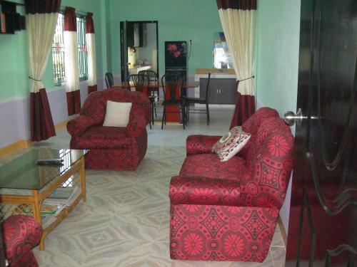 una sala de estar con 2 sillas rojas y una mesa. en ApartmenT - Homestays, en Sylhet