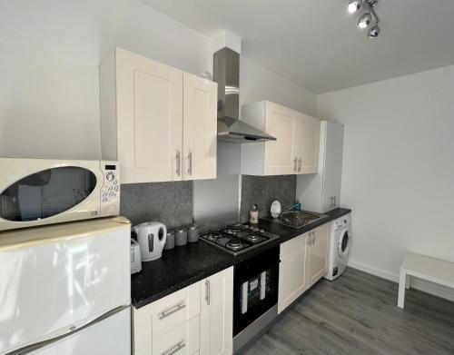 a kitchen with white cabinets and a microwave at 2 Bedroom Flat Ground Floor in Town Center in Wellingborough