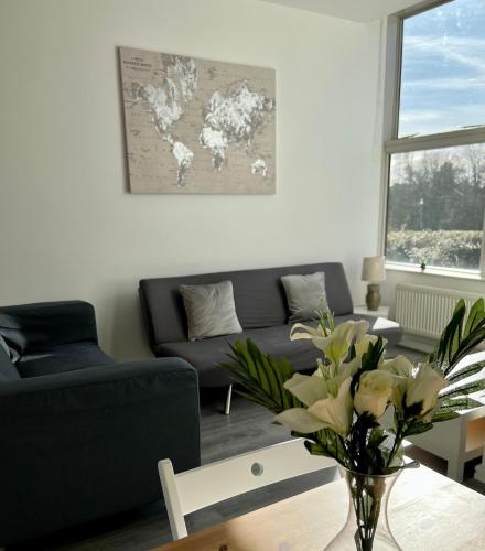 a living room with a couch and a table with flowers at 2 Bedroom Flat Ground Floor in Town Center in Wellingborough