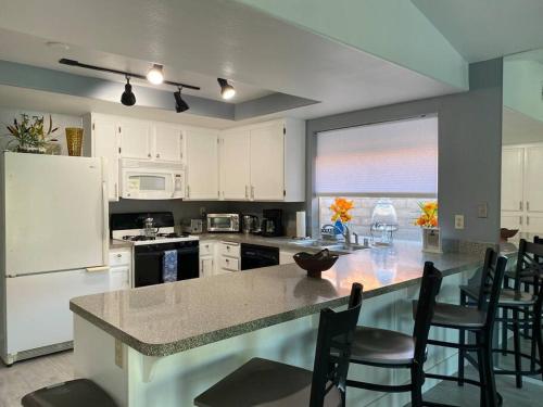 a kitchen with white cabinets and a large island with chairs at Dreamy Palm Springs Villa w Pool, Spa, Great Views in Palm Springs