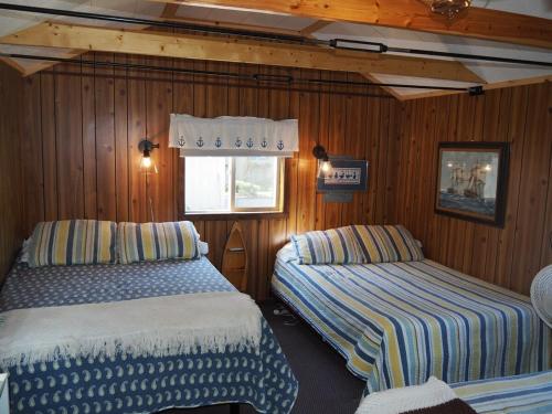 2 łóżka w pokoju z drewnianymi ścianami w obiekcie Sleeping Bear Riverside Cabins - Cabin #1 w mieście Honor