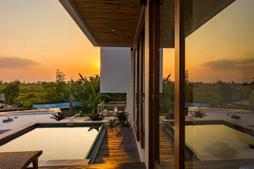 a house with a pool and a sunset at Pagi Villas by Betterplace in Canggu