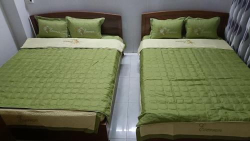 two beds sitting next to each other with green sheets at Eo Gió Motel in Hưng Lương