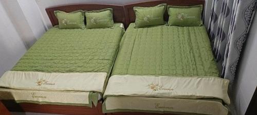 two beds sitting next to each other with green sheets at Eo Gió Motel in Hưng Lương