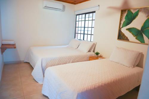 two beds in a room with a window at Cabaña Macondo in Coveñitas