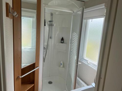 une salle de bain avec une douche avec une porte vitrée dans l'établissement Mobilhome familial avec piscine, tennis et jeux à Blonville-sur-Mer - FR-1-712-60, à Blonville-sur-Mer