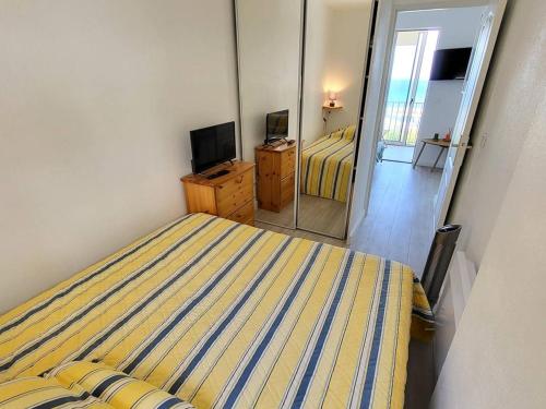 - une chambre avec un lit rayé et un miroir dans l'établissement T2 climatisé - Wi-Fi - Parking - Piscine - Tennis - 200m plages & commerces - FR-1-316-322, à Six-Fours-les-Plages