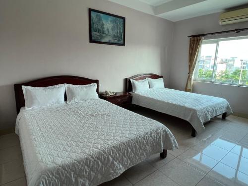 a hotel room with two beds and a window at Khách Sạn Sông Lô in Hải Dương