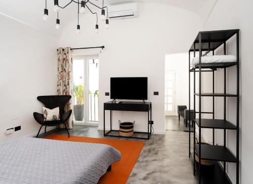 ein Schlafzimmer mit einem Bett, einem TV und einem Stuhl in der Unterkunft Casa800 in Capri