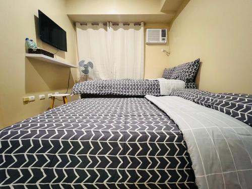 a bedroom with a bed with a black and white comforter at * * * E Best Value Room for up to 3 in Iloilo City