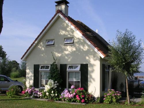 una casa blanca con flores delante en Attractive holiday home with jetty, en Steendam