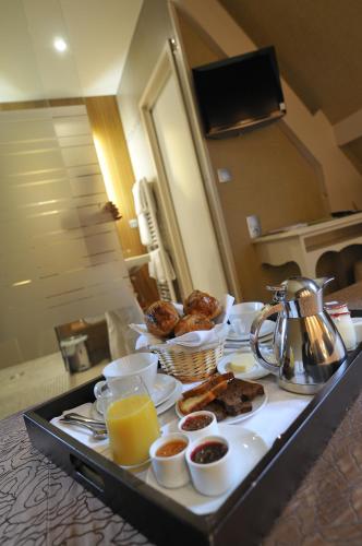 a breakfast tray with breakfast foods and orange juice at Le Manoir du Lys, The Originals Relais in Bagnoles de l'Orne