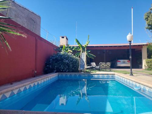 Habitación con baño privado y estacionamiento في سان مارتين: مسبح امام جدار احمر