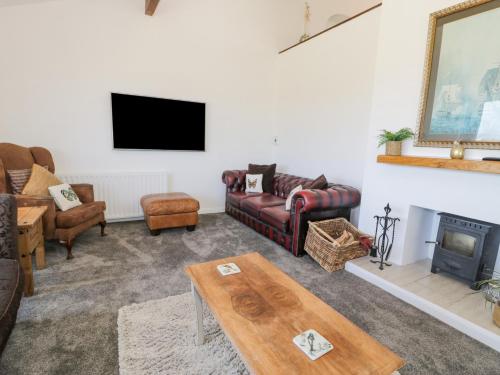 a living room with couches and a tv and a table at Minerva in Holyhead