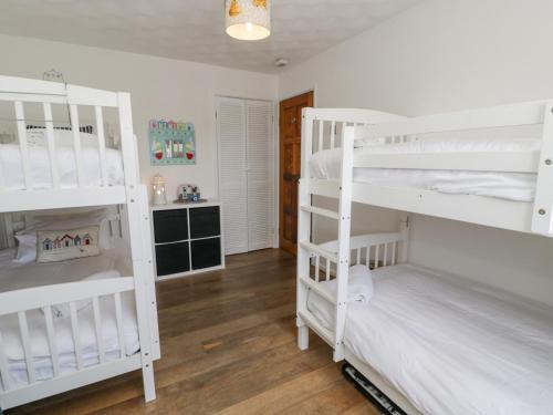 two white bunk beds in a room with wooden floors at Minerva in Holyhead