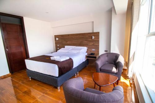 a hotel room with a bed and two chairs at Hotel Cumbre Real Airport - Arequipa in Arequipa