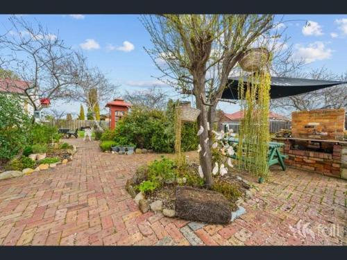 a garden with a tree and a table and a building at Sorell Barracks in Sorell