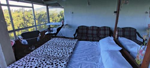a bedroom with a bed and two chairs and a window at Rohana Estate Lodging & Camping in Kandy