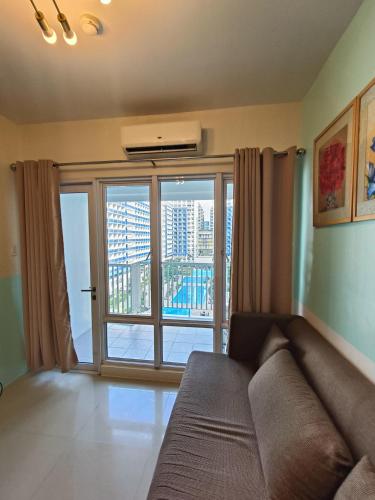 a living room with a couch and a large window at Premiere Haven MOA Staycation in Manila