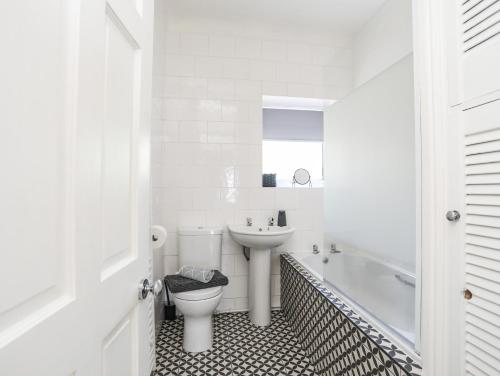 a white bathroom with a toilet and a sink at Bryn Tirion - Penrhynside in Conwy